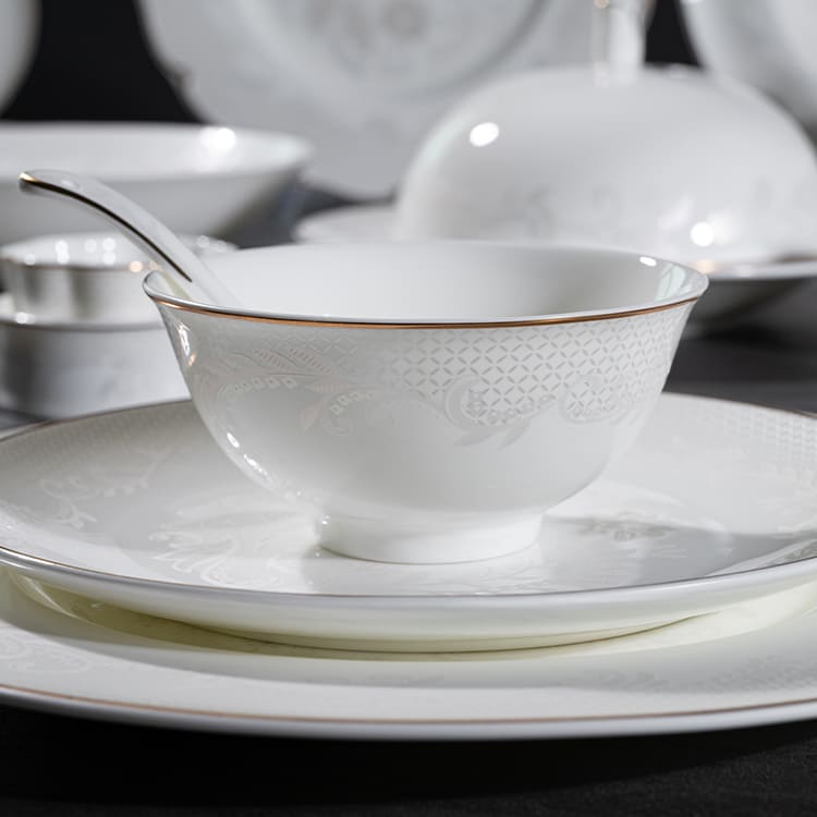 An elegant bone china bowl and plate set with intricate floral patterns and gold rims.