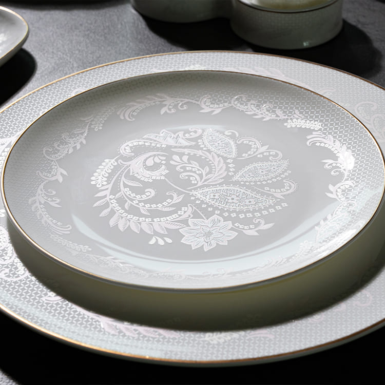 A sophisticated bone china dinner plate with intricate floral patterns and an elegant gold rim.