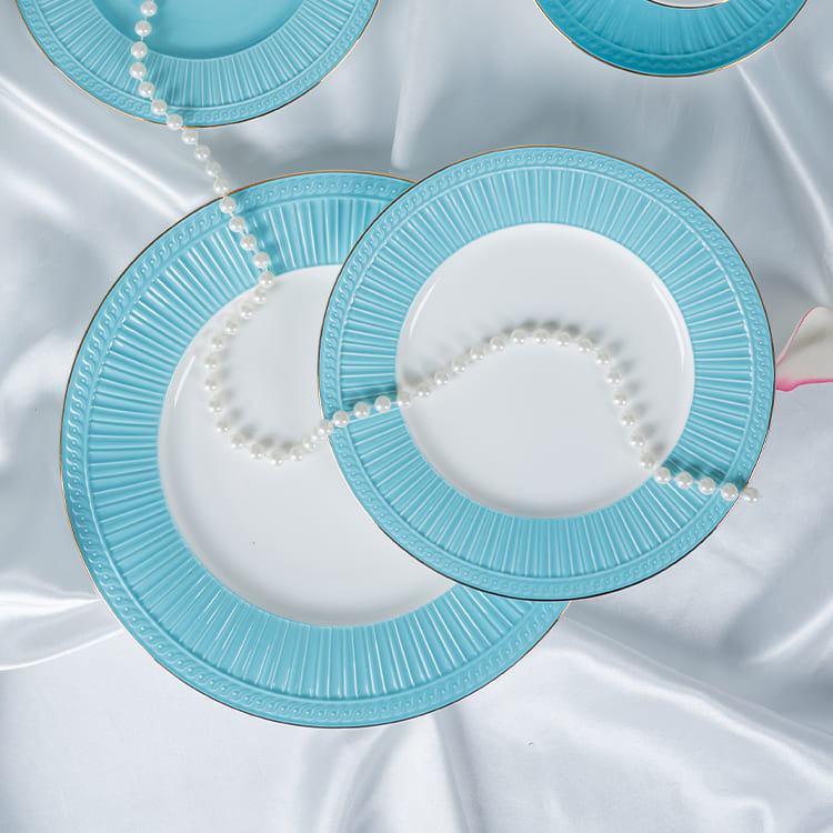 This image showcases a pair of blue bone china plates, elegantly arranged with strands of pearls on a white satin tablecloth.