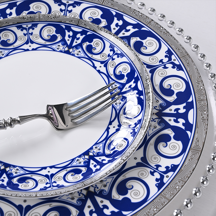 This image showcases a close-up view of an intricately designed blue and white bone china plate, part of a luxurious dinnerware set.