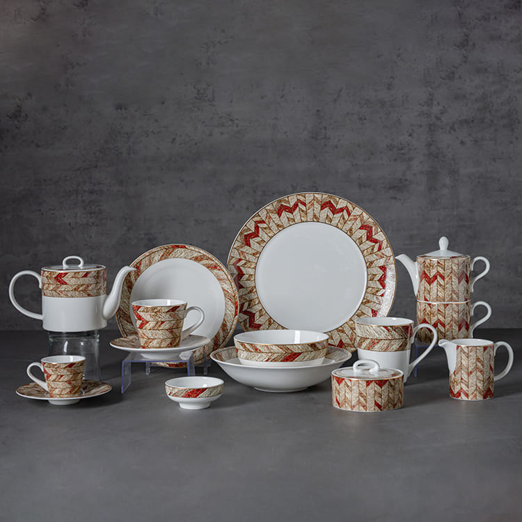 The set includes various pieces such as plates, cups, saucers, teapots, and bowls, all adorned with intricate decals in a rich red and gold pattern.
