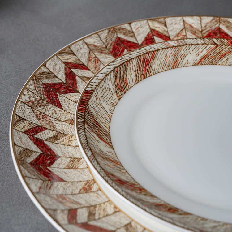 The image focuses on the detailed design of the dinnerware plates, highlighting the intricate red and gold patterns that adorn the rims.