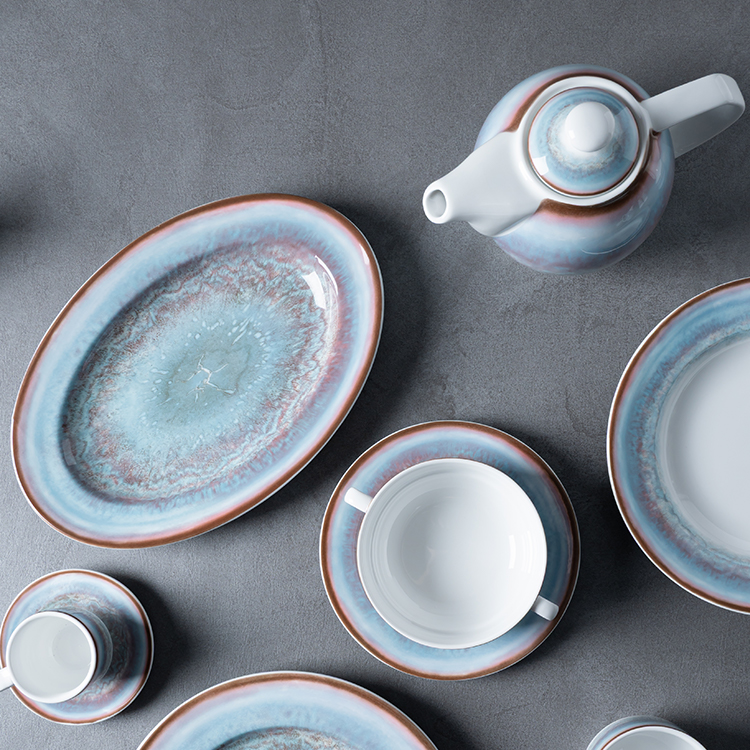 This image presents an elegant porcelain tea set, featuring a teapot, a soup bowl with a saucer, an oval serving plate, and a small cup with a saucer.