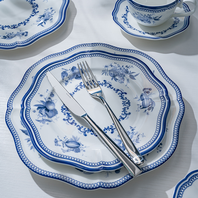 The image features a beautifully arranged porcelain plate setting, complete with a knife and fork, highlighting the intricate blue floral design that adorns the dinnerware.