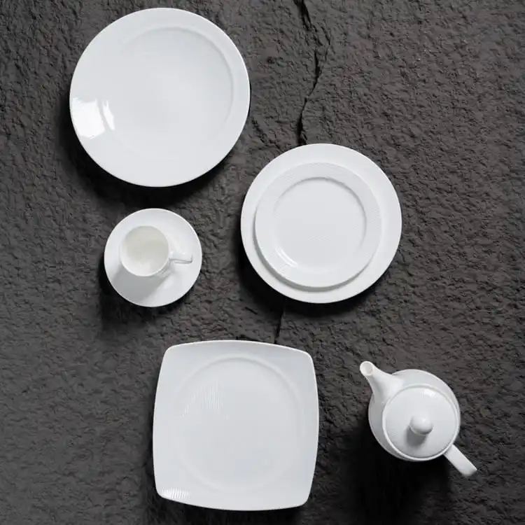This image showcases a minimalist display of fine porcelain dinnerware, arranged against a textured dark background.