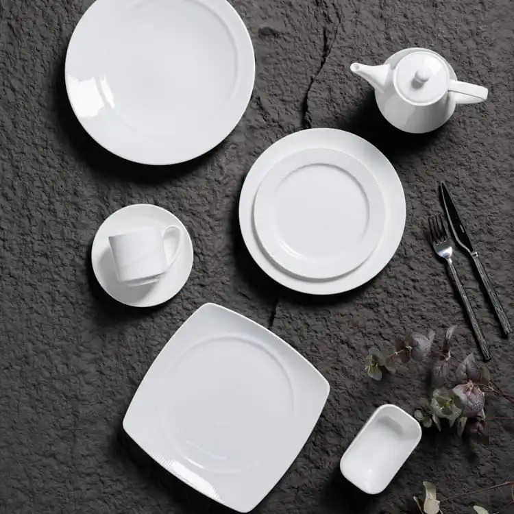 This image features a refined arrangement of fine porcelain dinnerware, set against a textured dark background.