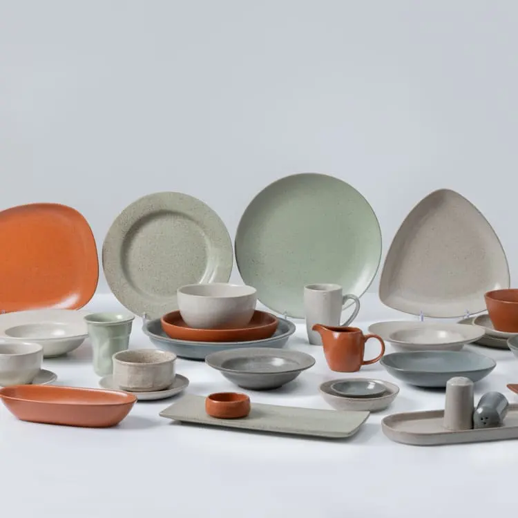 This image showcases a diverse collection of porcelain dinnerware, featuring an array of plates, bowls, cups, and serving dishes in various shapes and colors.