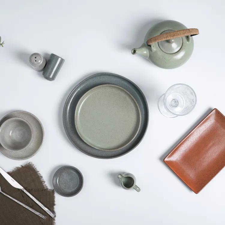 This image presents an eclectic table setting featuring a variety of porcelain dinnerware pieces, including plates, bowls, a teapot, and a glass.