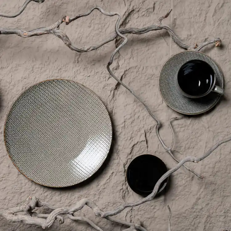 This image features a dark grey porcelain dining set, artfully arranged with natural elements like twigs, creating a harmonious blend of elegance and nature.