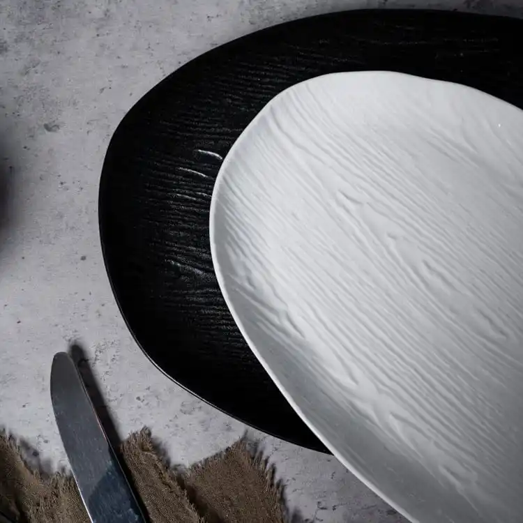 This image features a close-up view of two porcelain plates, one black and one white, showcasing their intricate textured surfaces.