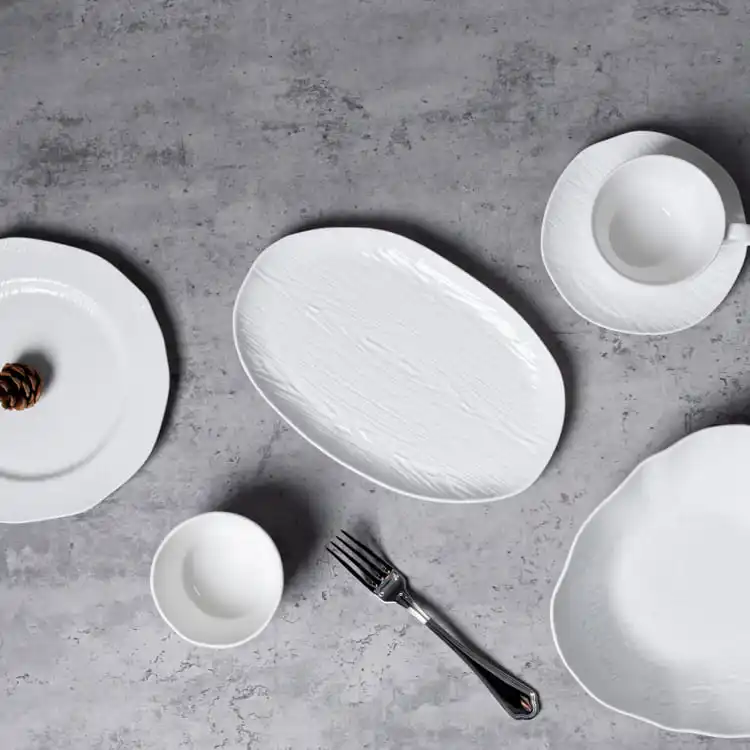 This image showcases a minimalist dinnerware arrangement featuring a selection of white porcelain pieces, including plates, cups, and bowls.