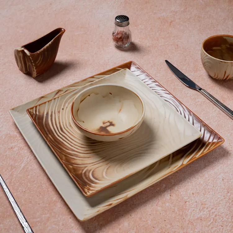 The arrangement includes a large square plate, a smaller square plate, and a round bowl, all adorned with a wood grain pattern in earthy tones.