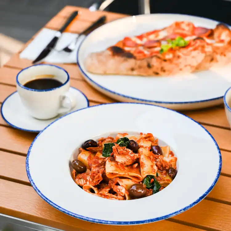 The pasta is complemented by a pizza in the background, creating a harmonious blend of Italian cuisine.