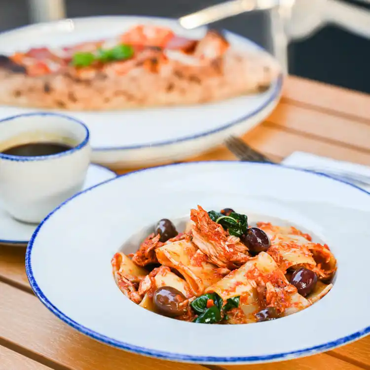 The plate's elegant design highlights the vibrant colors of the pasta, garnished with olives and herbs.
