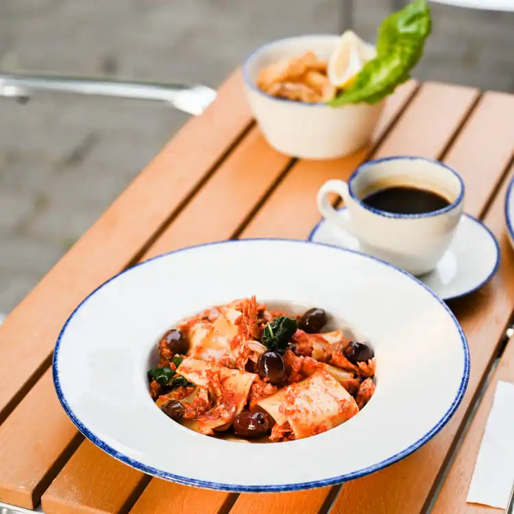 This image showcases a beautifully plated pasta dish served on a fine porcelain plate with a distinctive blue rim.