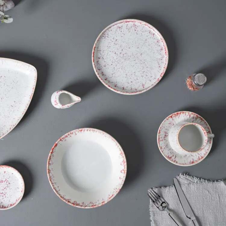 The set includes a round plate, a bowl, and a cup with a saucer, each featuring the distinctive pink speckle pattern.