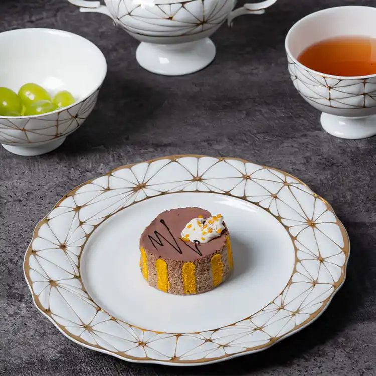 This image captures a luxurious dessert presentation on a bone china plate with a gold rim.