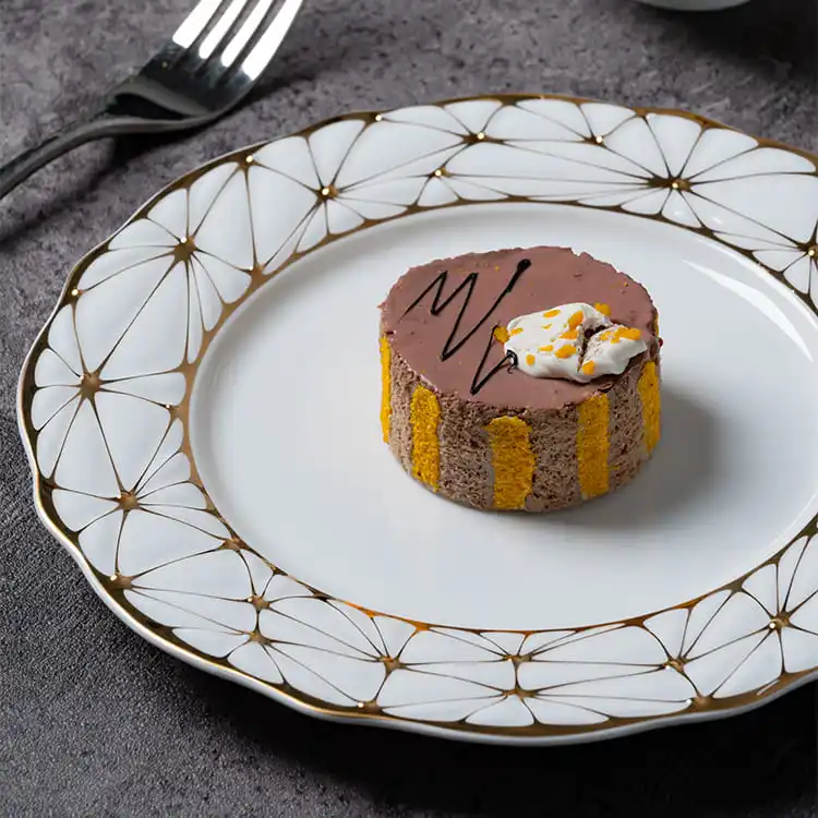 This image showcases an elegant dessert plate made of bone china with a gold rim.
