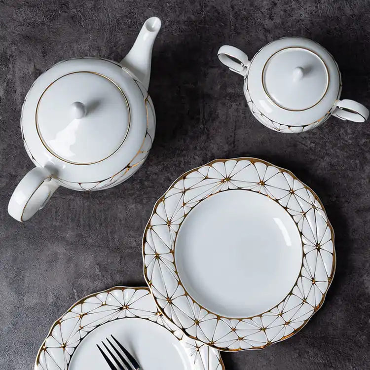 This image features a refined tea service set, including a teapot, sugar bowl, and two bone china plates with a gold rim.