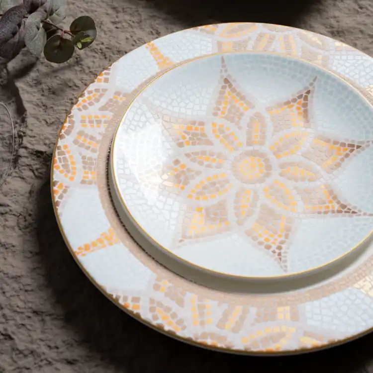 This image highlights the intricate details of decorative porcelain dinnerware, featuring a close-up view of the mosaic patterns in warm tones of orange and brown.