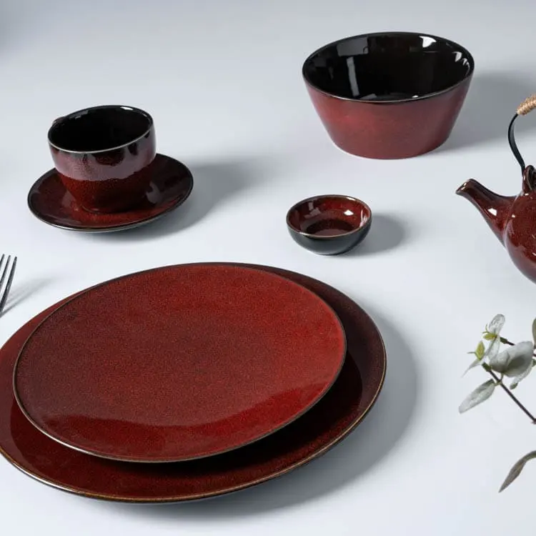 This image showcases a dining set from the crimson red porcelain collection, including plates, bowls, a teapot, and a cup with saucer.