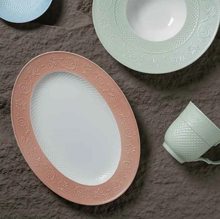 Flat lay of empty bone china embossed plates and mug, displaying uniform glaze, emboss texture as specification sample for multi-location restaurant standardization.