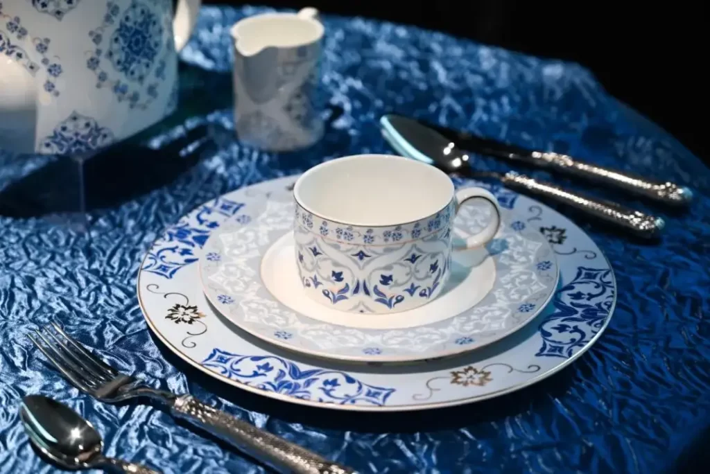 Close-up of PITO blue and white porcelain teacup and saucer set on a blue tablecloth.
