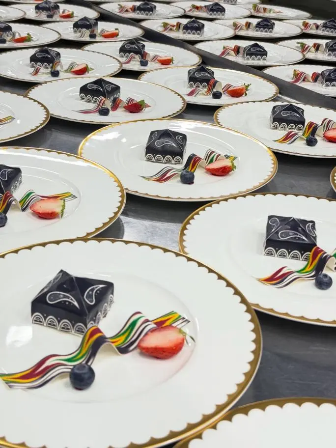 Close-up of custom fine china dessert plates with gold scalloped edges, elegantly plated for Versal's luxury banquets.