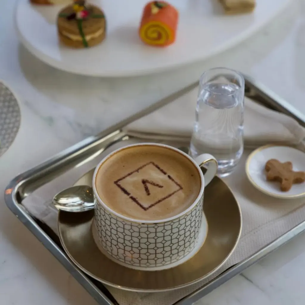 Latte with hotel logo served in a PITO custom bone china cup with geometric grid design and gold rim.