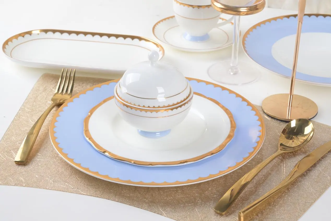 Elegant fine china table setting with light blue and gold-rimmed plates and gold cutlery for Versal's luxury events.