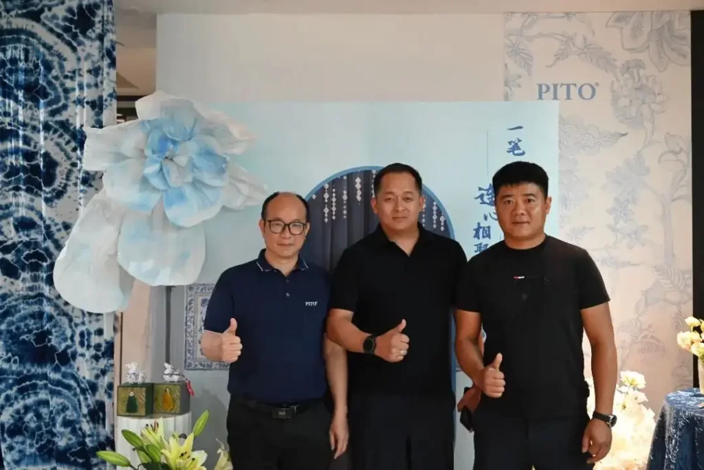Three men from PITO and Kyrgyzstan give thumbs up at the museum, surrounded by blue and white decor.