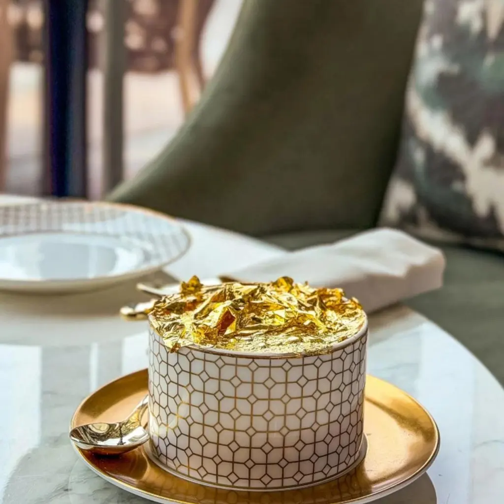 Luxury dessert topped with edible gold leaf served in a PITO custom bone china container with gold saucer.