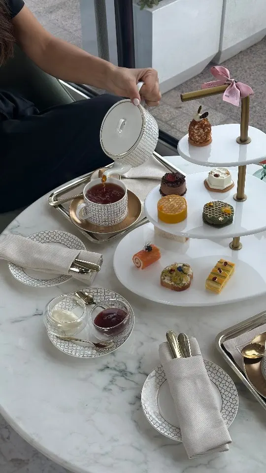 Guest pouring tea from a PITO geometric grid pattern teapot into a matching cup during afternoon tea.