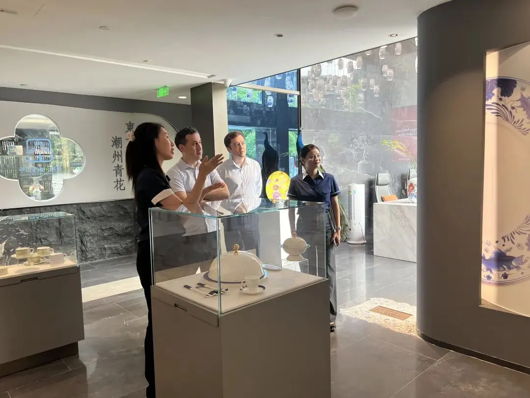 PITO staff introduces heritage bone china exhibits in glass showcase to consul and delegation at Chaozhou Blue and White Porcelain Culture Museum.