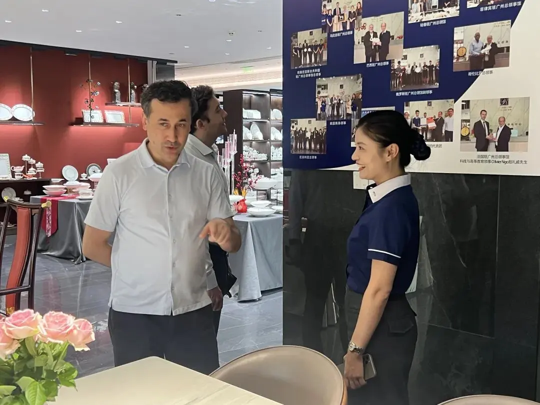Consul talks with PITO management beside the consular cooperation photo wall, exchanges ideas on diplomatic porcelain tableware cooperation and cultural communication.