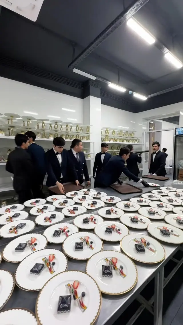 Versal venue staff plating desserts on custom fine china plates in the banquet kitchen, showcasing elegant gold-rimmed tableware.